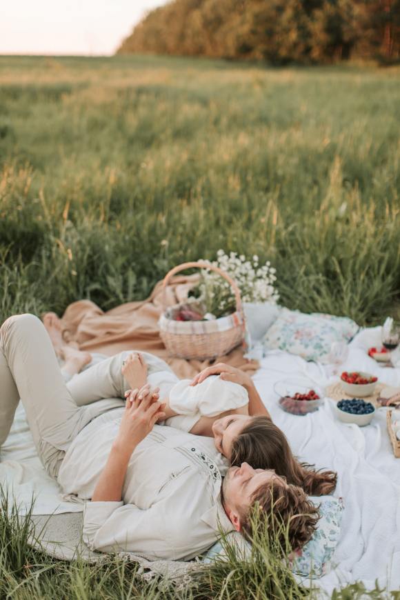 Loving Couple Laying Down After A Picnic In An Open Field